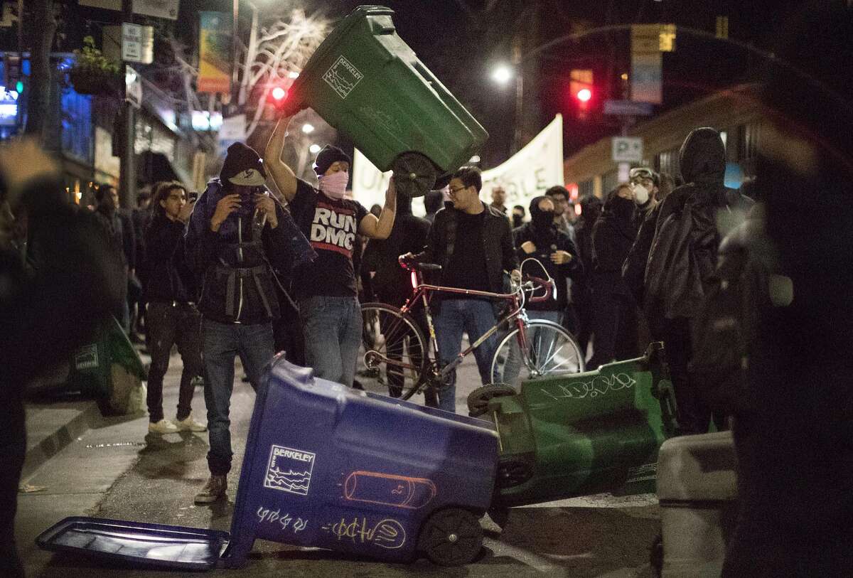 A protesters dumps a trash can in the middle of Telegraph Ave. on Wednesday, Feb. 1, 2017 in Berkeley, Calif.