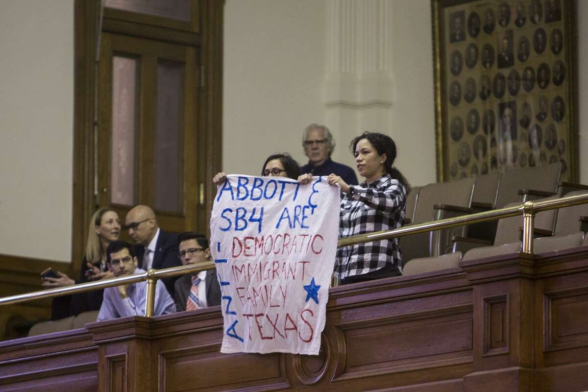 Protesters display a sign before being removed from the Senate Gallery during the Senate Committee on State Affairs meeting about Senate Bill 4 at the Texas Capitol in Austin, Texas on February 2, 2017.
