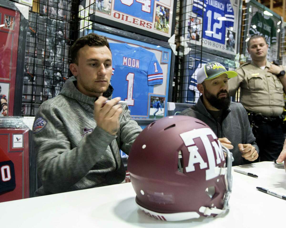 Johnny Manziel prepares to sign a Texas A&M helmet during a paid autograph event at a store in a Katy mall Thursday night. ﻿