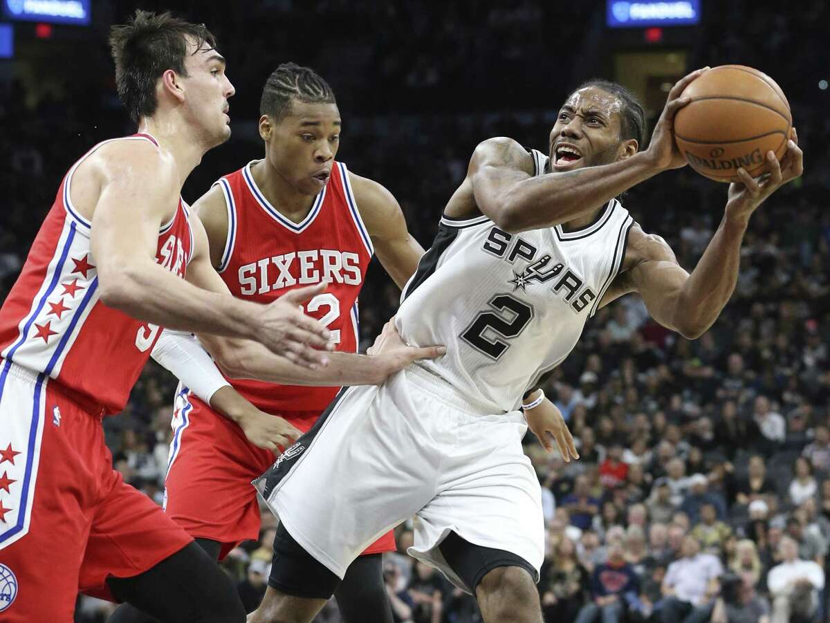 Kawhi Leonard pulls away and makes a fall away jumper after beng fouled by Dario Saric with Richaun Holmes following the play as the Spurs host the Sixers at the AT&T Center on February 2, 2017.