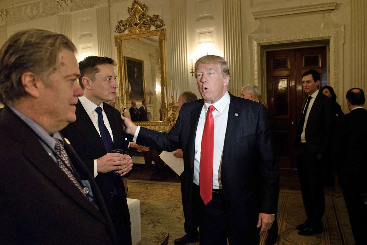Trump advisor Steve Bannon, left, watches as President Donald Trump greets Elon Musk.