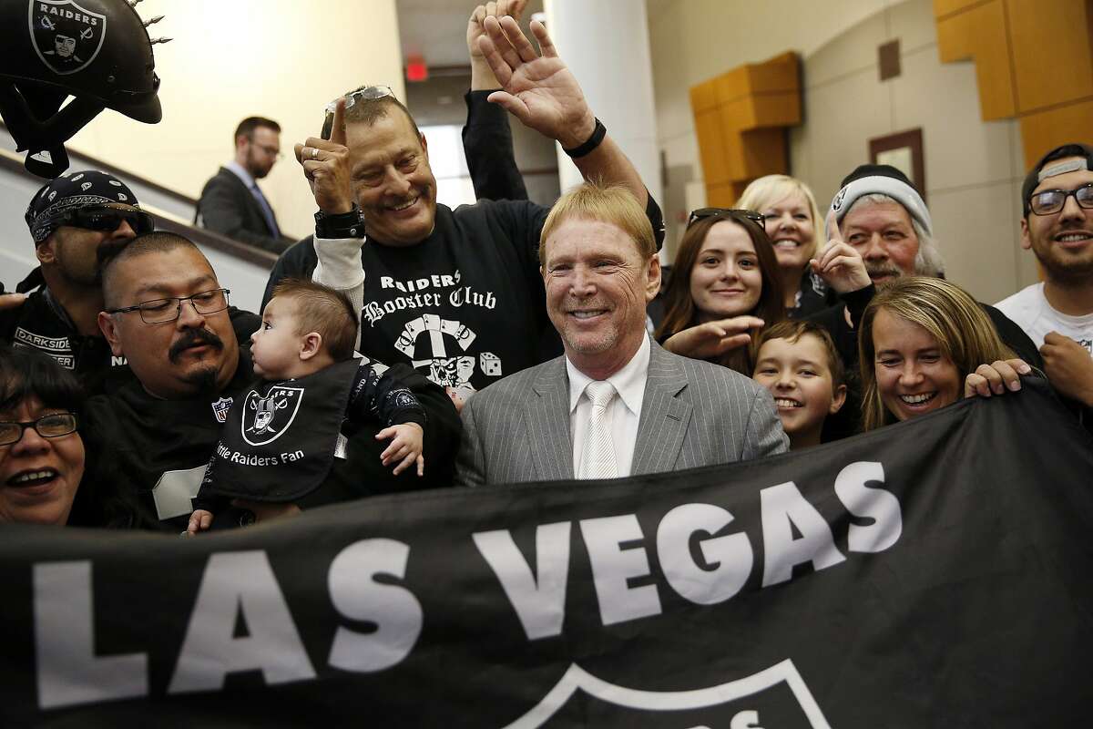 FILE - In this April 28, 2016, file photo, Oakland Raiders owner Mark Davis, center, meets with Raiders fans after speaking at a meeting of the Southern Nevada Tourism Infrastructure Committee in Las Vegas. America's most popular sport is in the midst of its greatest migration in a quarter century. In a little over a year, three NFL franchises have either moved, announced a resettlement or filed paperwork seeking to relocate.