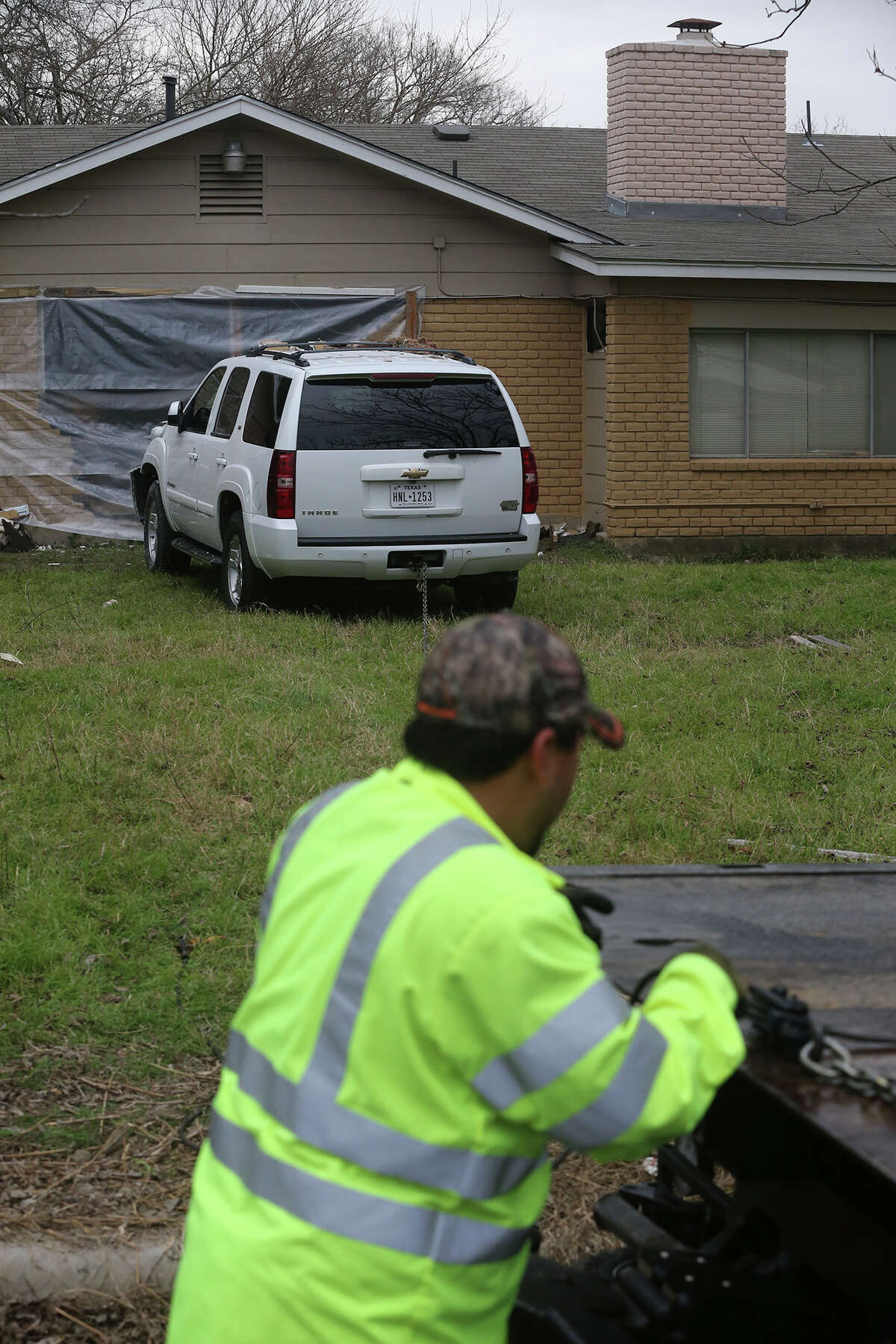 A tow truck driver prepares to remove a Chevy Tahoe Friday February 3, 2017 from the back yard of a home after crashing into a home on the 11,000 block of Janet Lee Drive. An officer at the scene said the driver was intoxicated and was not injured. The vehicle came to a halt after crashing through several fences and hitting the house.