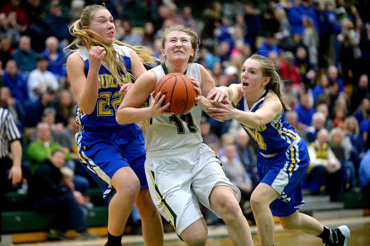 Dow's Ellie Taylor, center, goes for a layup while Midland's Jeni Grinwis, left, and Alex VanSumeren, right, try to stop her on Friday at H. H. Dow High School.