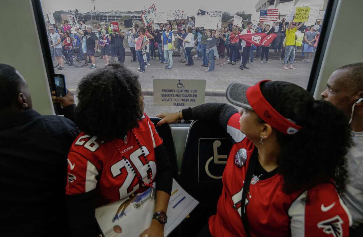 Dr. Juana Mendenhall, left, and Alicia Saunders, both of Atlanta, attended their first Super Bowl game to support the Falcons. On the women's way to Reliant Stadium, protesters lined the streets outside their train, obeying traffic laws and orders from police to remain on the sidewalk.﻿