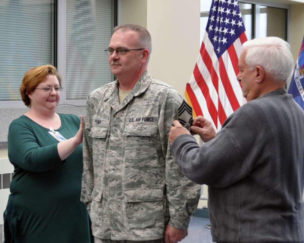 Wife Joan Peno and father Peter Peno tack new stripes onto Chief Master Sgt. Shawn Peno at Division of Military and Naar Affairs Headquarters. (Sgt. Major Corine Lombardo)