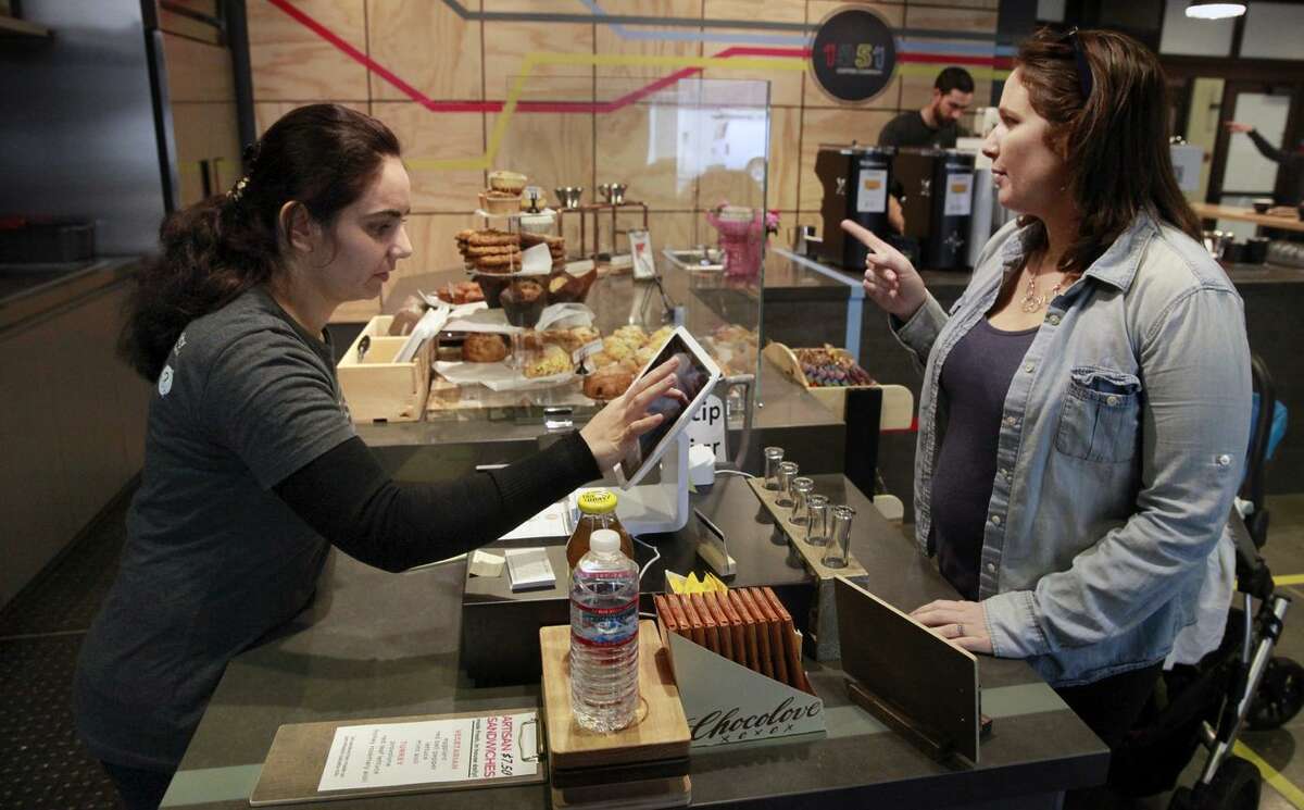 Nazira Babori (left), a refugee from Afghanistan, takes Sarah Gregson’s order Friday at 1951 Coffee Company. Babori recently fled Kabul, where she worked with the United Nations.