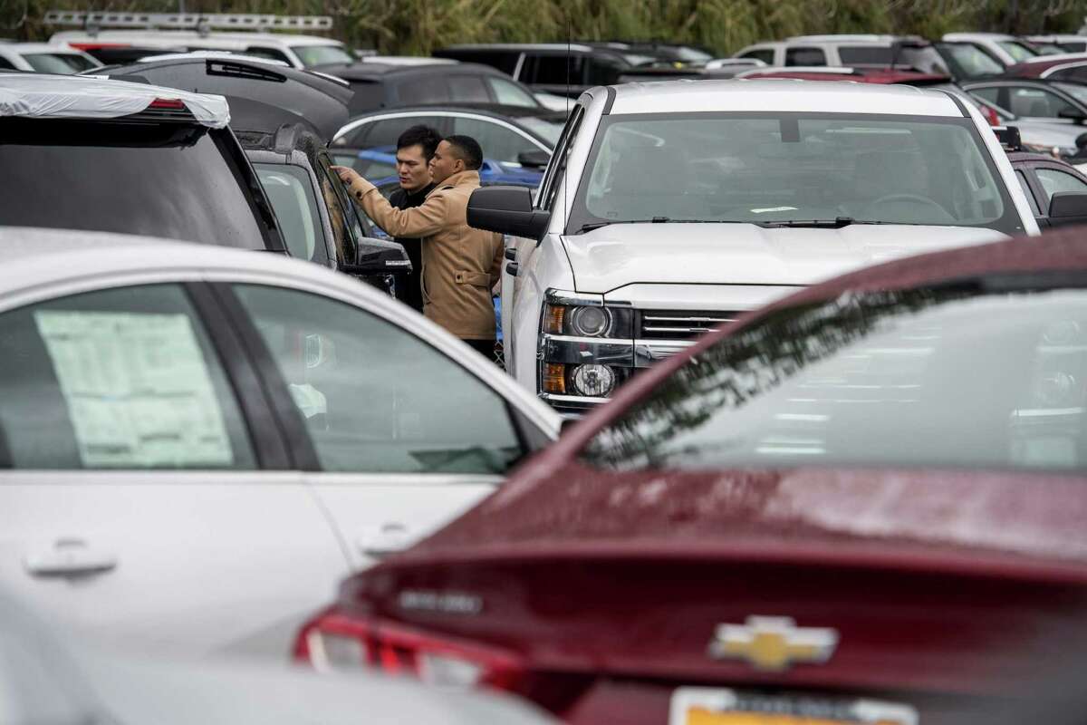 A salesman (right) helps a potential customer inspect a General Motors SUV at a California dealership. GM reported full-year net income of $9.4 billion, but an encore could be a lot harder. Overall auto sales are flattening in the U.S., GM’s biggest profit center, and car inventories are growing. Economic troubles linger in Europe and South America. And a new U.S. president wants to redo the North American Free Trade Agreement and could slap a border tax on imports from Mexico.