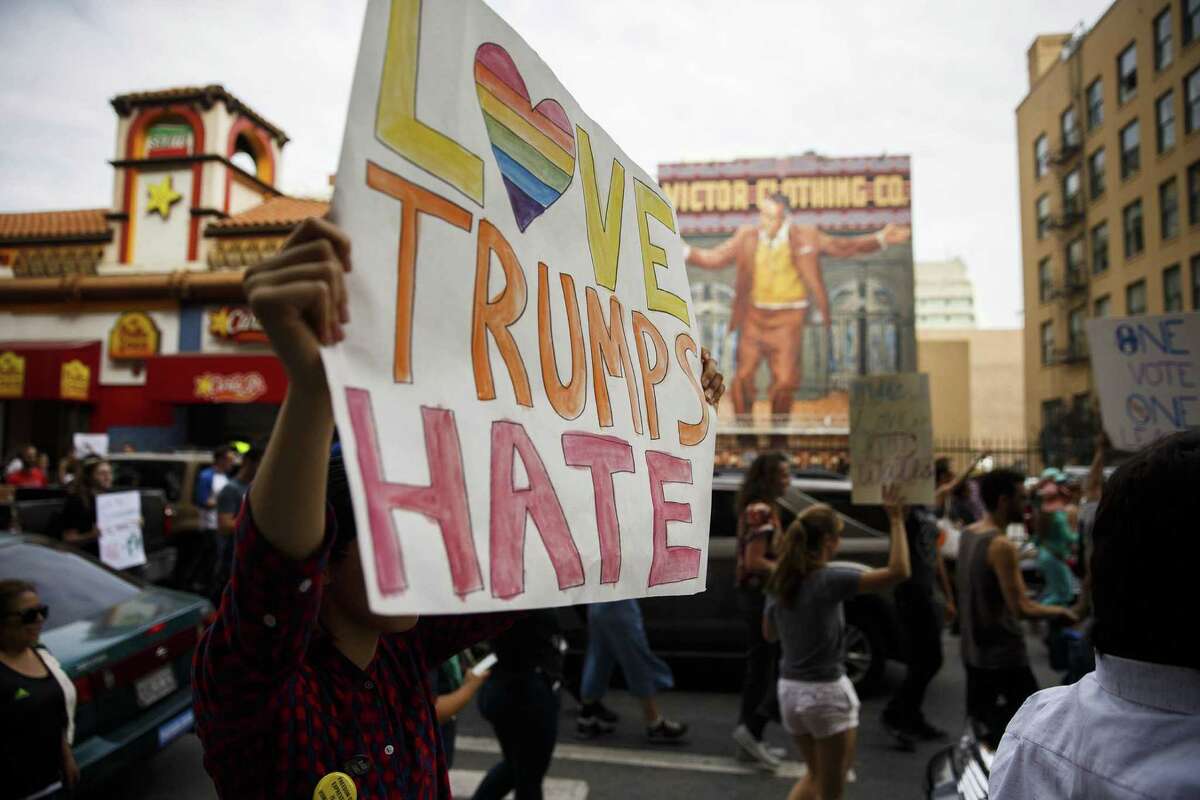 A demonstrator holds a “Love Trumps Hate” sign during a protest in Los Angeles. Readers express contrasting views on the protests.