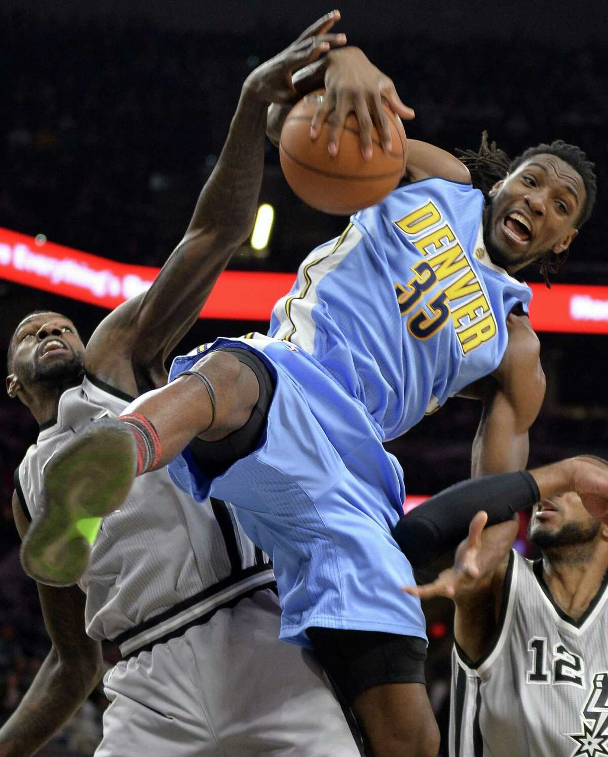 Denver Nuggets forward Kenneth Faried (35) falls as he jumps for the rebound against the Spurs’ Dewayne Dedmon during the first half on Feb. 4, 2017, in San Antonio.