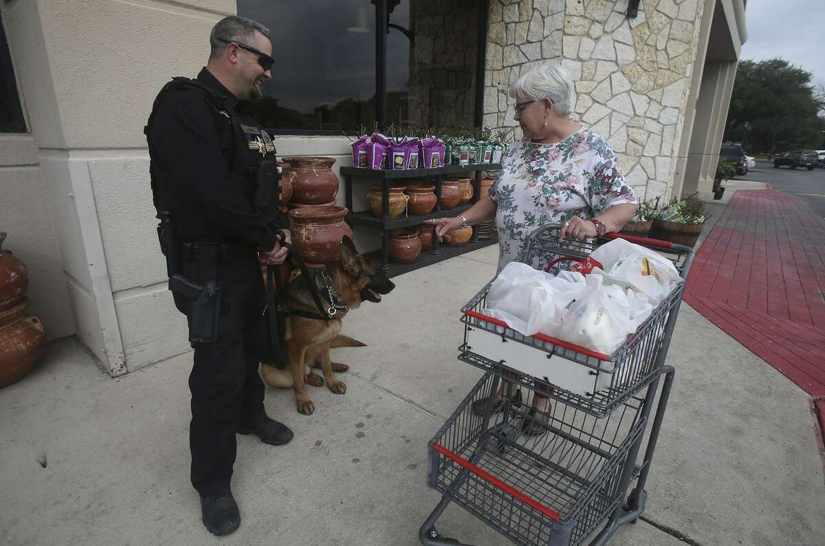 Security officer Justin Owen (left) speaks Monday February 6, 2017 with H-E-B customer Jean Vargo (right) as Owen stands guard in front of the Lincoln Heights H-E-B store with S.E.A.L. Security canine officer "Fak" (cq) (seated, center). H-E-B is bringing canine security officers to seven stores in the San Antonio area as part of a partnership with Houston-based S.E.A.L. Security Solutions.