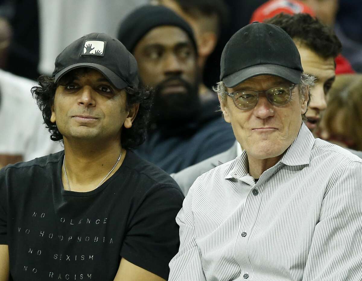 Film Director M. Night Shyamalan, left, sits with actor Bryan Cranston during the first half of an NBA basketball game between the Philadelphia 76ers and the San Antonio Spurs, Wednesday, Feb. 8, 2017, in Philadelphia. (Yong Kim/The Philadelphia Inquirer via AP)