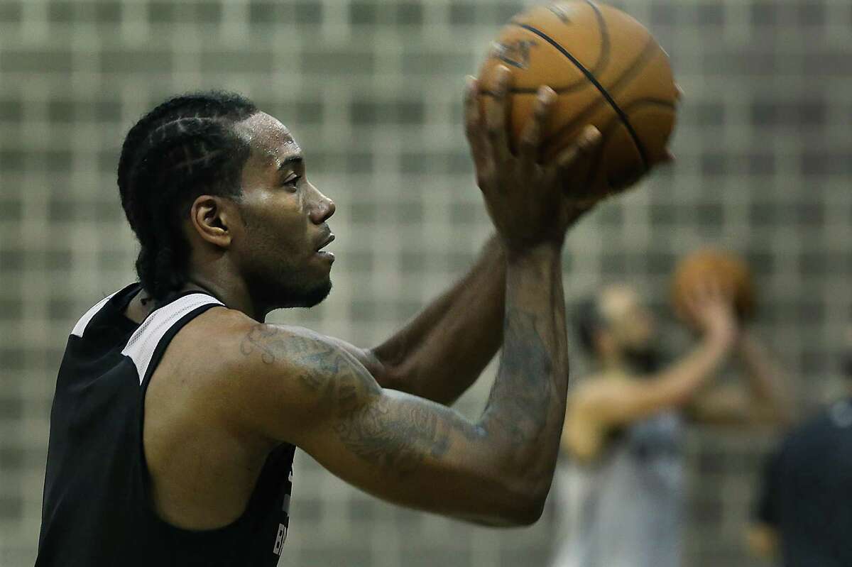 Spurs’ Kawhi Leonard (left) and Manu Ginobili (background at right) shoot free throws during practice at the practice facility in 2014.
