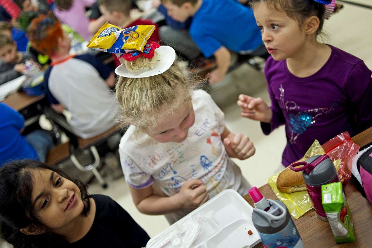 From left, Adams Elementary first-grader Tanisha Hasan, 6, gazes off as first grader Ellee Arnold, 7, balances pretzels on her donut hairdo which were put on her head by first grader Sera Dimulo, 7, right, during Wacky Hair Day on Friday at Adams Elementary. Kids wore their hair in various colors, styles and shapes as part of Adams Spirit Days. The next Spirit Day will be on Mar. 17, and the theme is Pure Michigan Day.