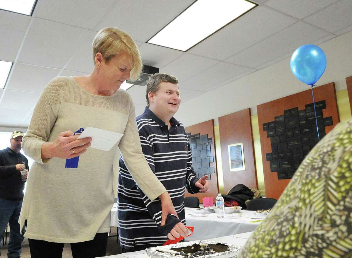 Greenwich resident and Blueberry farmer Philippa Orszulak, left, with her son, Graham Moore, pin a ribbon on a blueberry dish entry during the first annual Abilis Grahamberries Blueberry Bake-Off Contest at Abilis in Greenwich, Conn., Friday afternoon, Feb. 10, 2017. The contest was named after Abilis group home resident and blueberry farmer, Moore, seen here, whose parents Peter, and Philippa Orszulak, also seen here, own a blueberry farm in upstate New York called Blueberry Hill. Graham works for the farm delivering the blueberries to businesses in the Greenwich and Stamford area. The farm provided the blueberries for the contest. Graham, along with his parents, were the judges for the Abilis group home blueberry bake-off entries that involved around 60 Abilis clients said Erica Klair, director of marketing & communications for Abilis. The Life Skills Greenwich home was selected as the winner of the contest with its blueberry cheesecake.