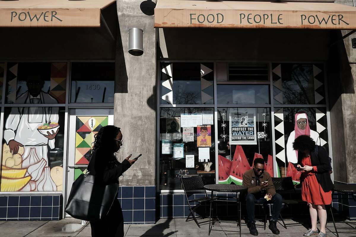 People sit at tables outside Mandela Foods Co-op in Oakland, CA on Friday, February 10, 2017.