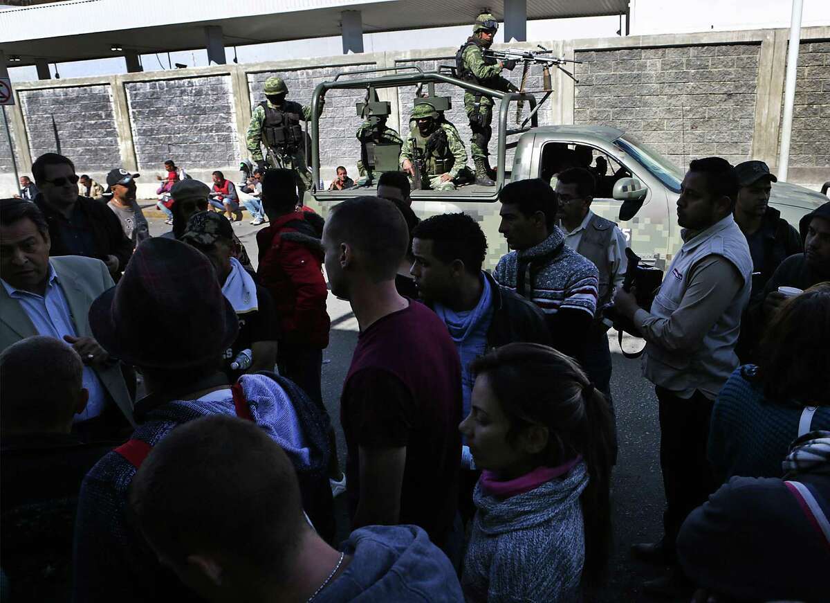 Cubans stuck in Nuevo Laredo, Mexico gather to hear a Tamaulipas immigration official near the International Bridge #1, as a military patrol vehicle passes by on Thursday, Jan. 26, 2017.