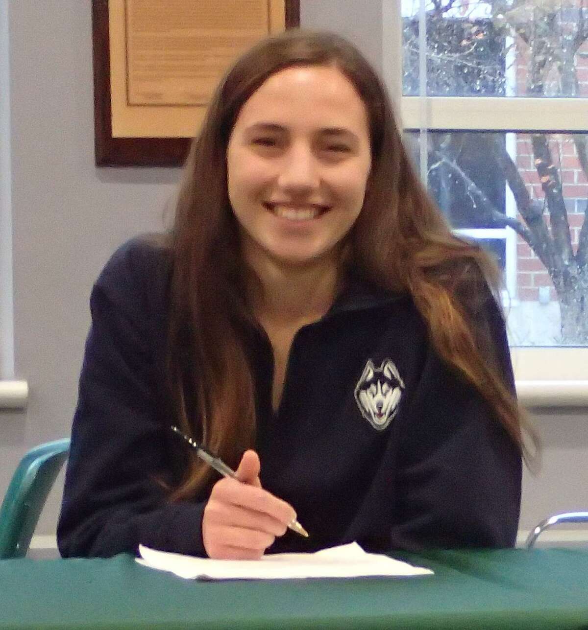 New Milford High School senior Mia Nahom signs her National Letter of Intent to compete for the cross country and track and field teams at UConn during a ceremony in the high school's library Nov. 15, 2016.