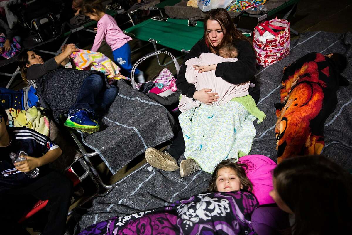 Gridley resident Shari Mota, right, tries to get her children to go to sleep in the evacuation center at the Butte County Fairgrounds in Chico, California on February 12, 2017.