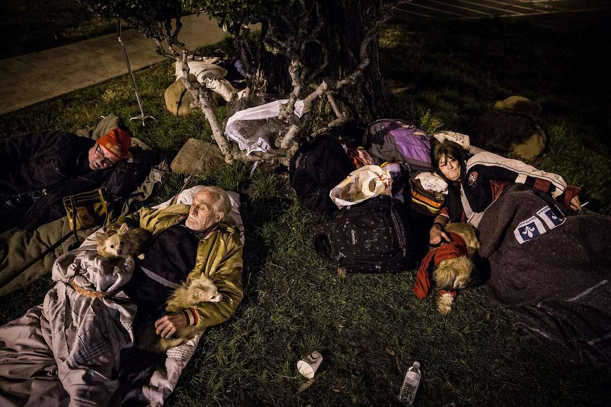 From left, Oroville residents Georgia Robert King, Jerry Lee Huggins and Anna Gibson sleep outside the evacuation center at the Butte County Fairgrounds in Chico, California on February 12, 2017. Pets aren't allowed in the evacuation center, so many pet owners stayed in their cars in the parking lot.