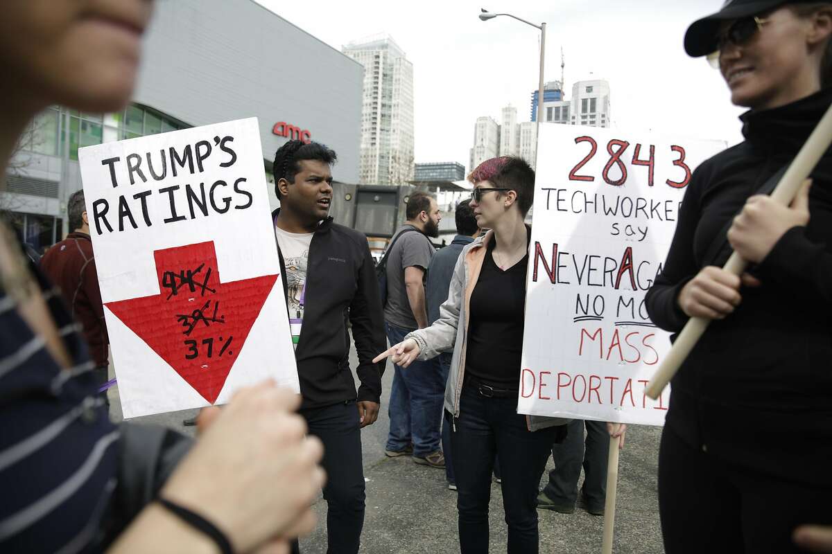 A security engineering tech worker (l to r) and Leigh, security at a start up, hold signs as they talk at the end of a rally calling on the tech industry to support all tech workers and to celebrate the 9th Circuit Court's decision to refuse to reinstate Trump's travel ban at the corner of Howard and Fourth Streets on Monday, February 13, 2017 in San Francisco, Calif.