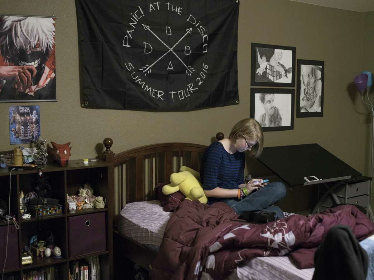 Alyssa Scott, 17, who is a senior at Stacey Junior-Senior High School, looks at her smartphone in her room in San Antonio, Texas on January 10, 2017. Scott's family moved to San Antonio from California late this past year and Scott was at risk of being unable to graduate on-time. The military interstate compact allows students transferred for their parent's military job, who would not qualify to graduate on time or with their preferred classes at their new school, to graduate from their previous school while attending classes wherever they have been transferred. Scott will graduate this coming May.