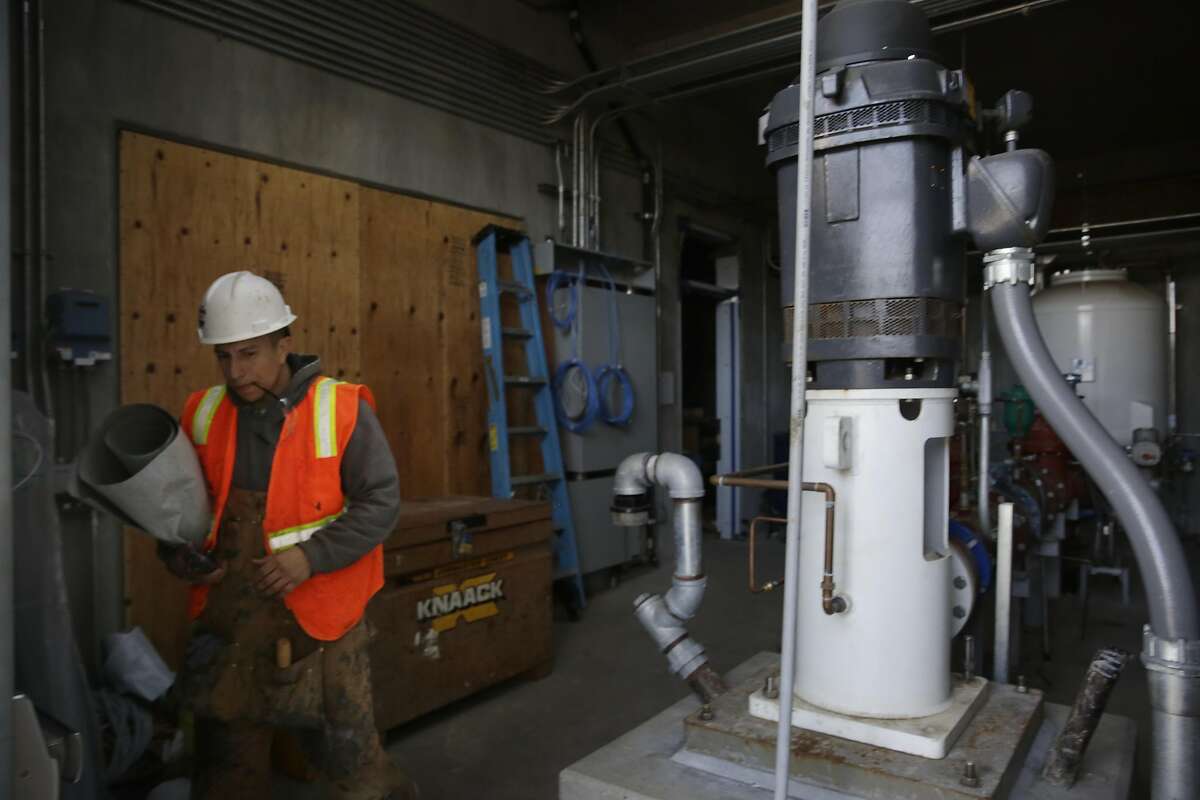 Israel Rivera, apprentice Pioneer Roofing, carries materials past the well pump while working on the exterior of the West Sunset Well Station on Tuesday, February 14, 2017 in San Francisco, Calif.