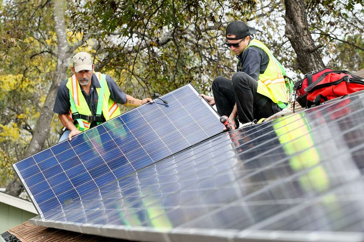 Solar installers put panels on the roof of a home in San Antonio.