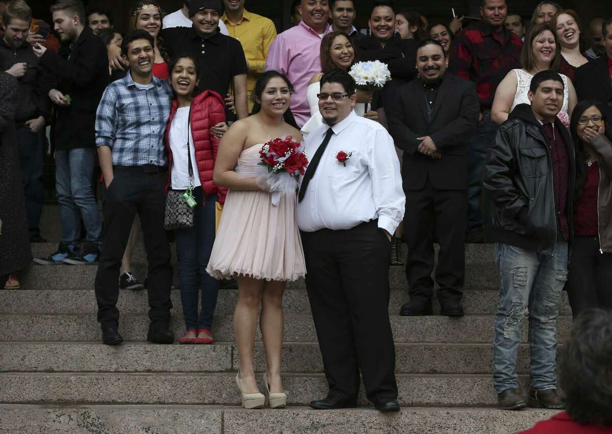 Savannah Rodriguez, 20, and Zachary Rodriguez, 21, wait for the start of the 10 a.m. Valentine's Day weddings in front of the Bexar County Courthouse, Feb. 14, 2017. Around 26 couples braved the cold winds to marry during the ceremony conducted by Bexar County Clerk Gerard Rickhoff.