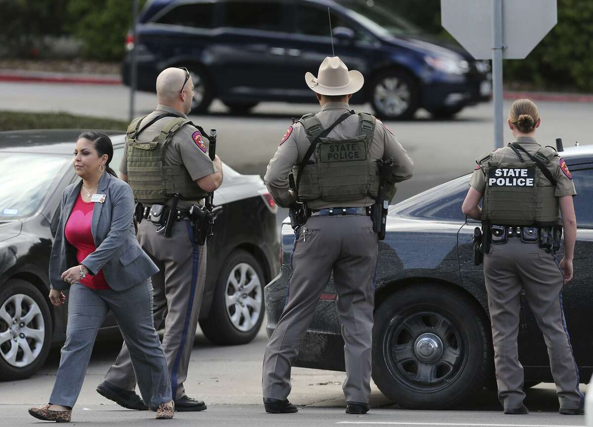 A civilian walks near state troopers after police looked for a suspect outside of North Star Mall on Feb. 14.