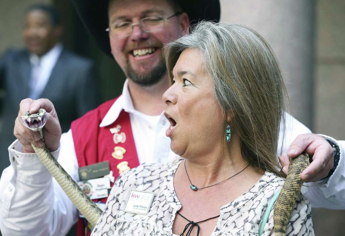 Judy Pierce from Dripping Springs gasps as Blake Stephens from the Sweetwater Jaycees holds the head of a snake on his shoulder at the Capitol as lawmakers debate the sanctuary cities bill in the Senate on February 7, 2017.