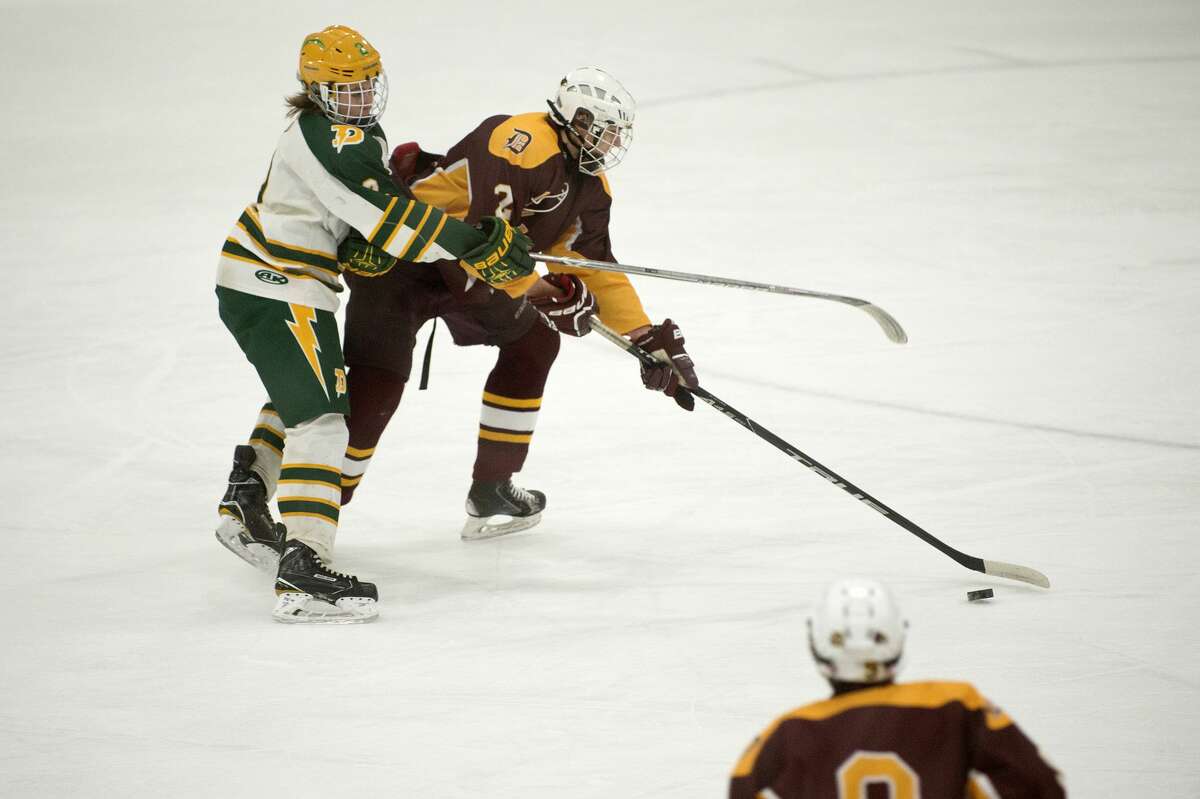 BRITTNEY LOHMILLER | blohmiller@mdn.net Davison High's Jourdan Schmidt works to control the puck while being defended by Dow High's Alec Newton in the first period of the Wednesday evening game.