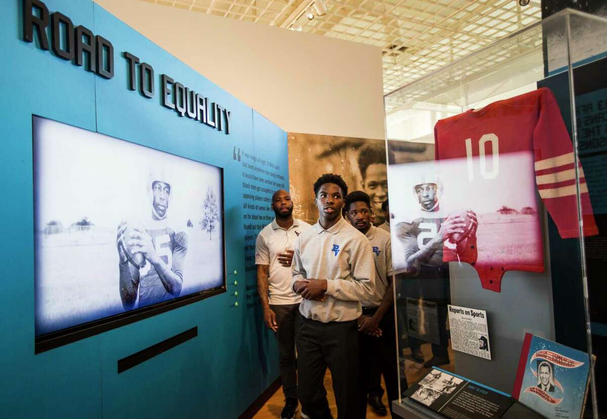 Houston Texans cornerback Johnathan Joseph, left, walks with students from Pro-Vision Academy during a tour of the Pro Football Hall of Fame's Gridiron Glory, traveling exhibit on the campus of Texas Southern University on Thursday, Feb. 16, 2017, in Houston.