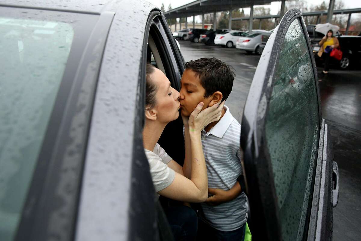 From left: Brittney Barber kisses her son Ethan, 7, as she drops him off at school on Thursday, Feb. 16, 2017 in Clovis, Calif. Barber is driving to Half Moon Bay to stay with a friend and shorten her commute to San Francisco, where she works as a Lyft driver. She''ll be away from home for three days to work 40-50 hours in her grey Honda Fit and then go back home to her family in Fresno County.