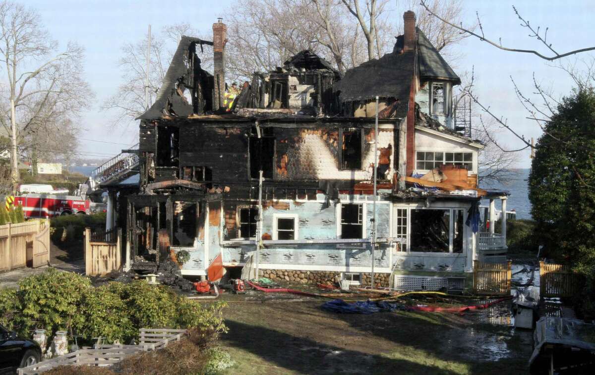 FILE - In this Dec. 25, 2011 file photo, firefighters investigate a house in Stamford, Conn., where an early morning fire left five people dead. The Hartford Courant reported Monday, May 9, 2016, that in a lawsuit deposition, contractor Michael Borcina said he lied to protect the children?’s mother Madonna Badger, who was the one who left a bag of fireplace ashes in a mudroom, which were suspected of causing the fire. (AP Photo/Tina Fineberg, File)