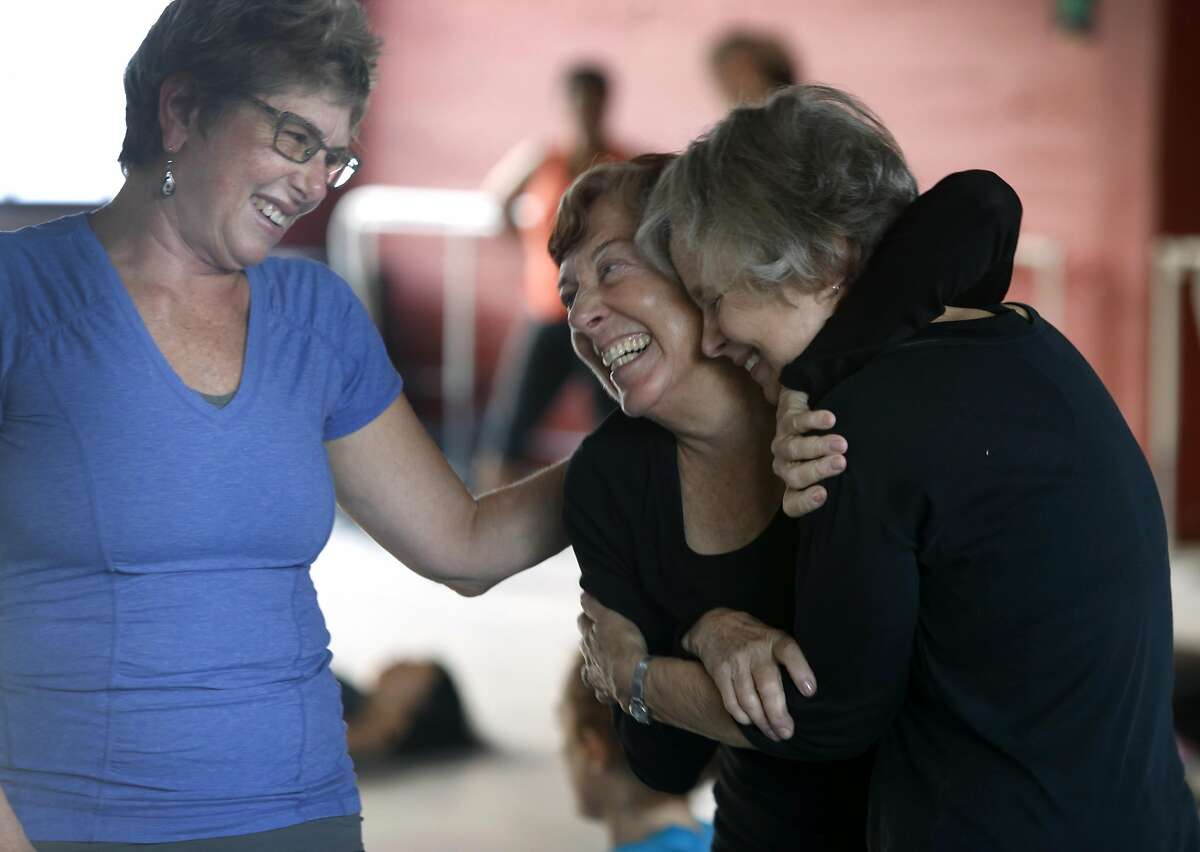 Angie Minkin (left), Sheila Mahoney (center) and Linda Blackstone hug before Amara Tabor-Smith's rhythm and motion class at ODC dance studios in San Francisco, Calif. on Saturday, Feb. 18, 2017. Many people are turning to dance as a way of relieving post-election stress.