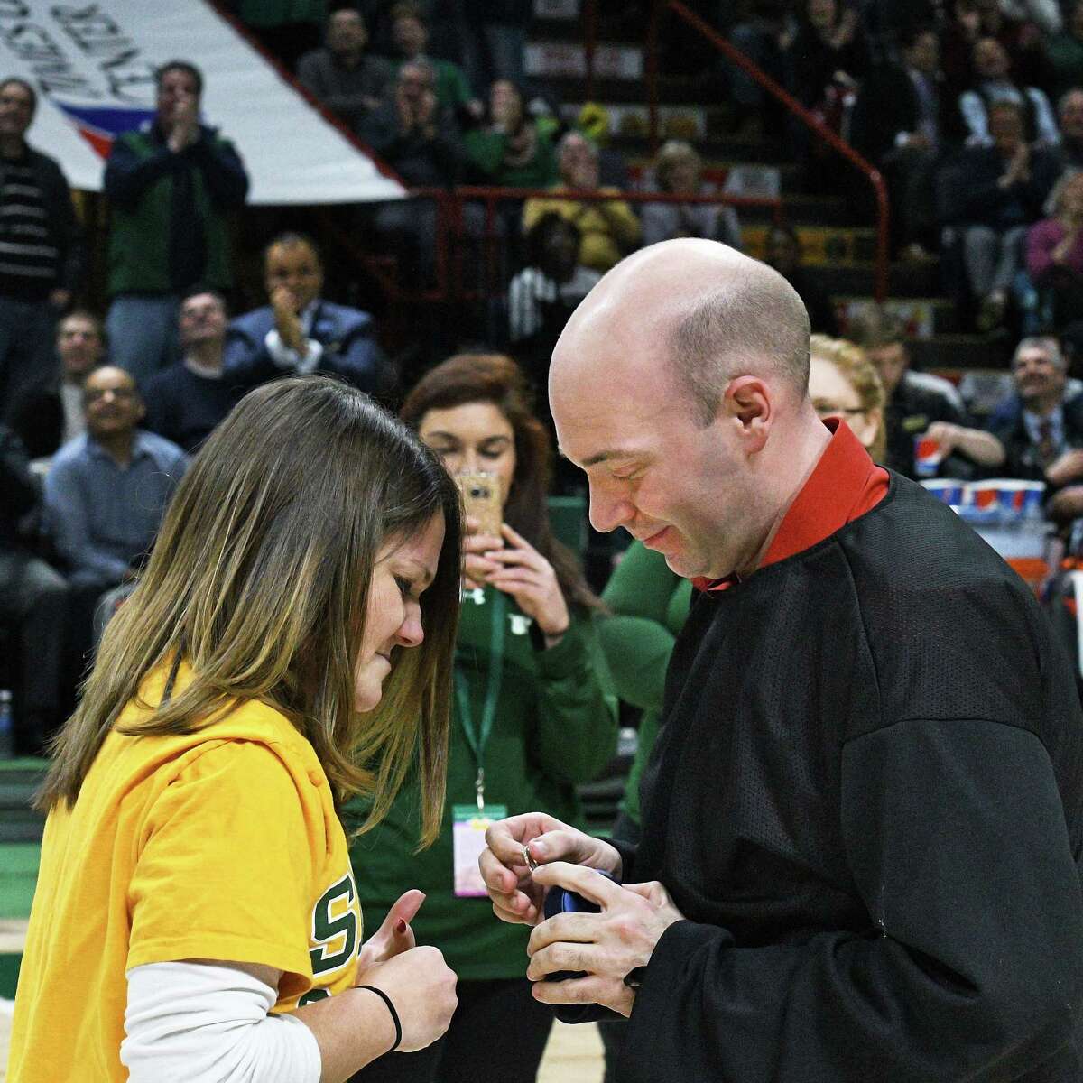 Erin Tobin, left, of Rensselaer is offered an engagement ring by Steve Duckett of Queensbury during a timeout in Thursday's Siena game at the Times Union Center on Feb. 16, 2017 in Albany, N.Y. She accepted his proposal. (John Carl D'Annibale / Times Union)