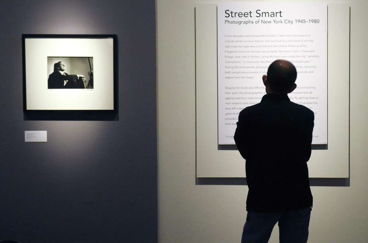A man reads the exhibition statement of the new "Street Smart" photography exhibit beside Herman Leonard's 1950 photograph of Tony Bennett at the Bruce Museum in Greenwich, Conn. Sunday, Feb. 19, 2017. The display features photographs of New York City from 1945 to 1980 by Larry Fink, Herman Leonard, Leon Levinstein, John Shearer, and Garry Winogrand. Street Smart provides "a glimpse at life in the city during the post-war period and at how street-savvy New Yorkers navigated its bustling landscape."