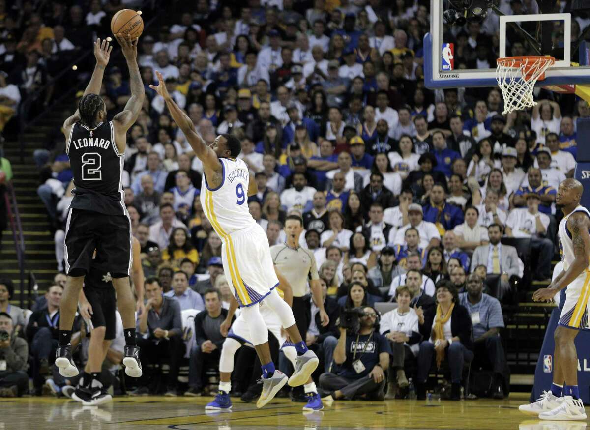 Kawhi Leonard (9) shoots over Andre Iguodala (9) in the second half as the Golden State Warriors played the Spurs in their season opener at Oracle Arena in Oakland, Calif., on Oct. 25, 2016.
