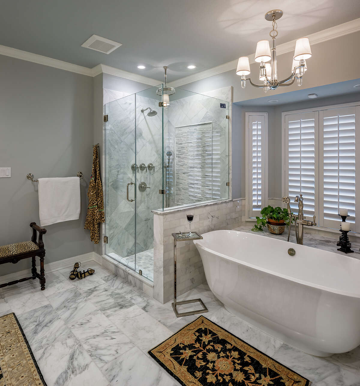 The Megnas' former shower with a wall of glass blocks was transformed with frameless glass walls and marble tile.