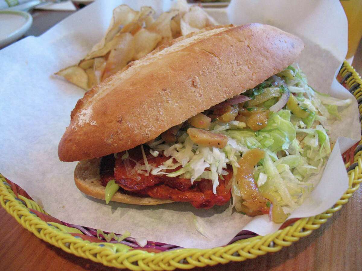 The torta al pastor comes with marinated pork, pineapple, red onion salad, lettuce and avocado cream.