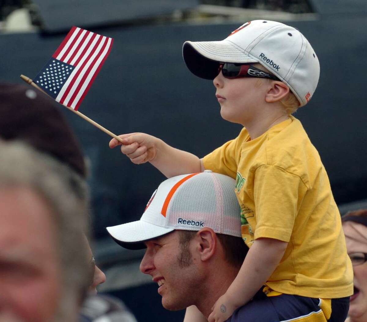 Aiden Courtney, of Bridgeport, waves the US flag while sitting atop his dad Chris' shoulders, during the Wings and Wheels 2010 car and air show at Sikorsky Memorial Airport in Stratford, Conn. on Saturday May 29, 2010.