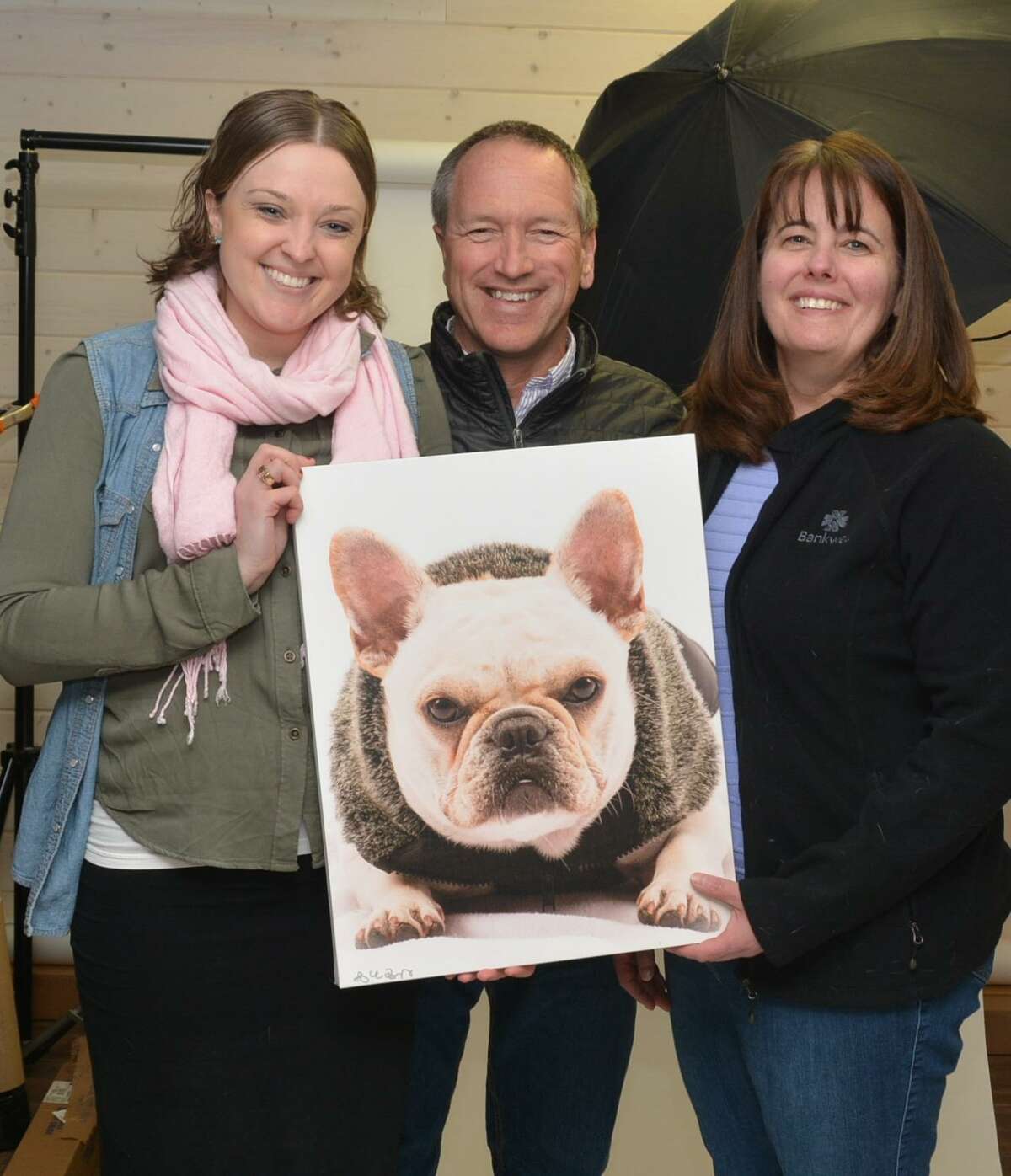 Bankwell Marketing Assistant Lucy French, photographer Mike Bagley and Ann Mitrione, Bankwell in Wilton branch manager, pose with a photo of a dog seeking adoption.