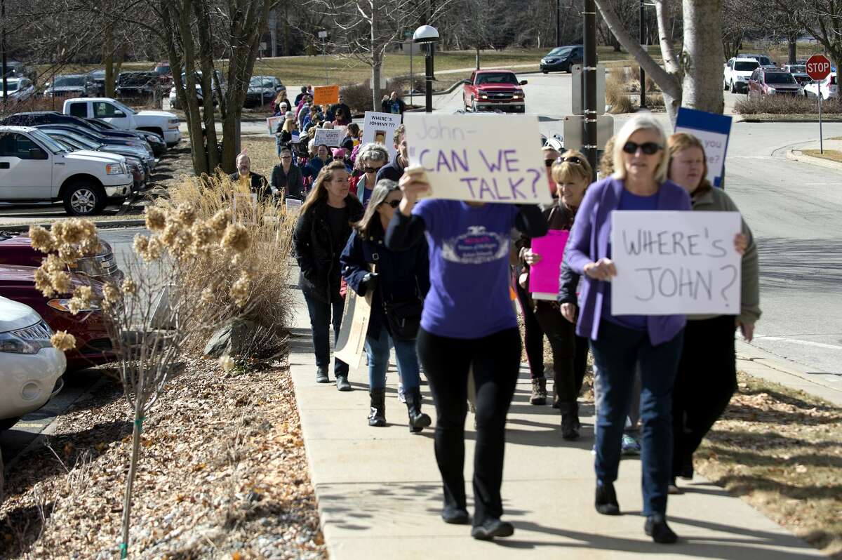 BRITTNEY LOHMILLER | blohmiller@mdn.net More than 50 people march up McDonald Street in Midland to U.S. Rep. John Moolenaar's Midland office to request a public town hall with Moolenaar Thursday afternoon. The gathering and march was organized through Facebook by The Women of Michigan Action Network.