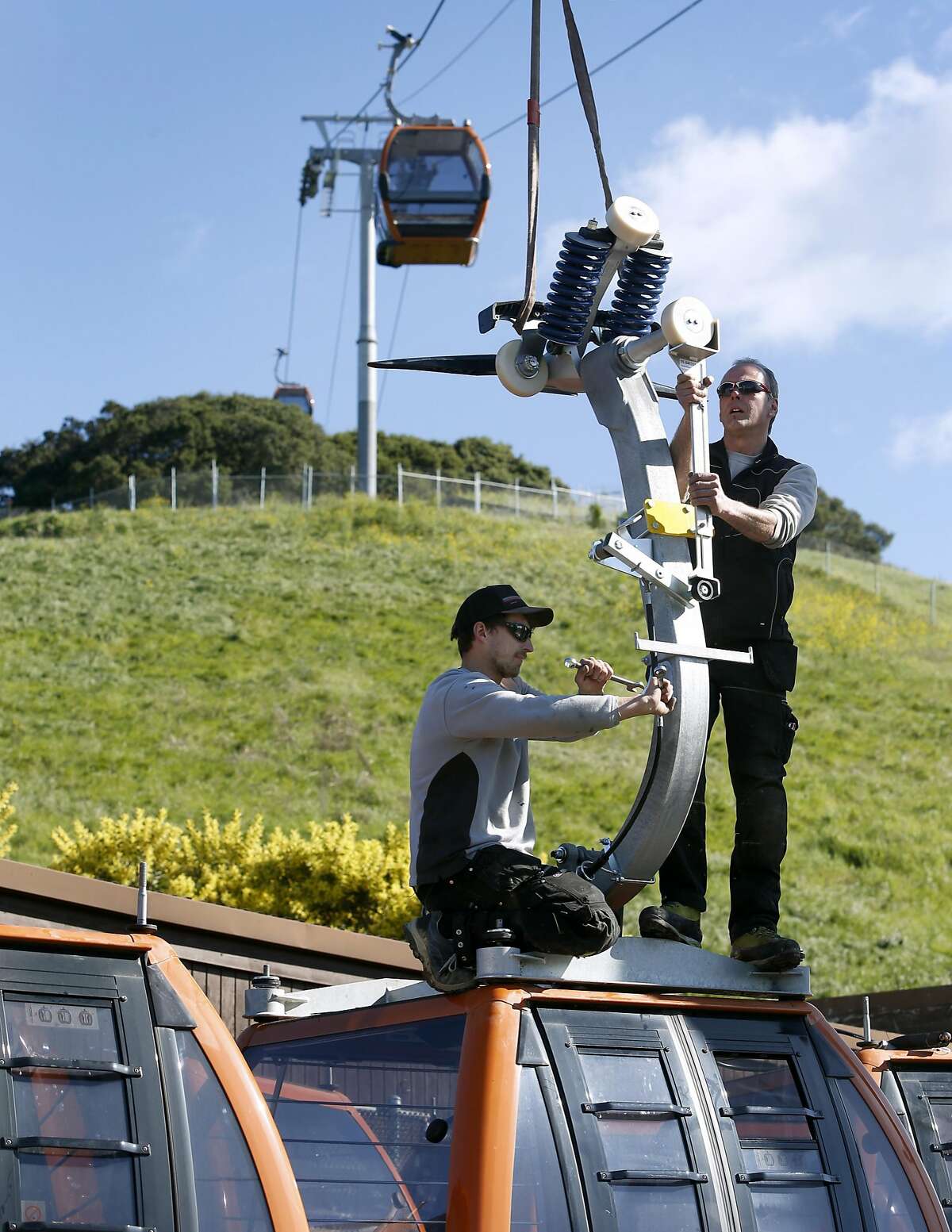 Severin Karter (left) and Martin Moser connect an arm onto the top of a cabin before it's suspended from a gondola system that will carry visitors to the Oakland Zoo's new California Trail exhibit in Oakland, Calif. on Thursday, Feb. 23, 2017. The gondola and restaurant, with a sweeping view of the Bay Area, is scheduled to open in June of this year with the entire exhibit inhabited with native California creatures slated to open in 2018.