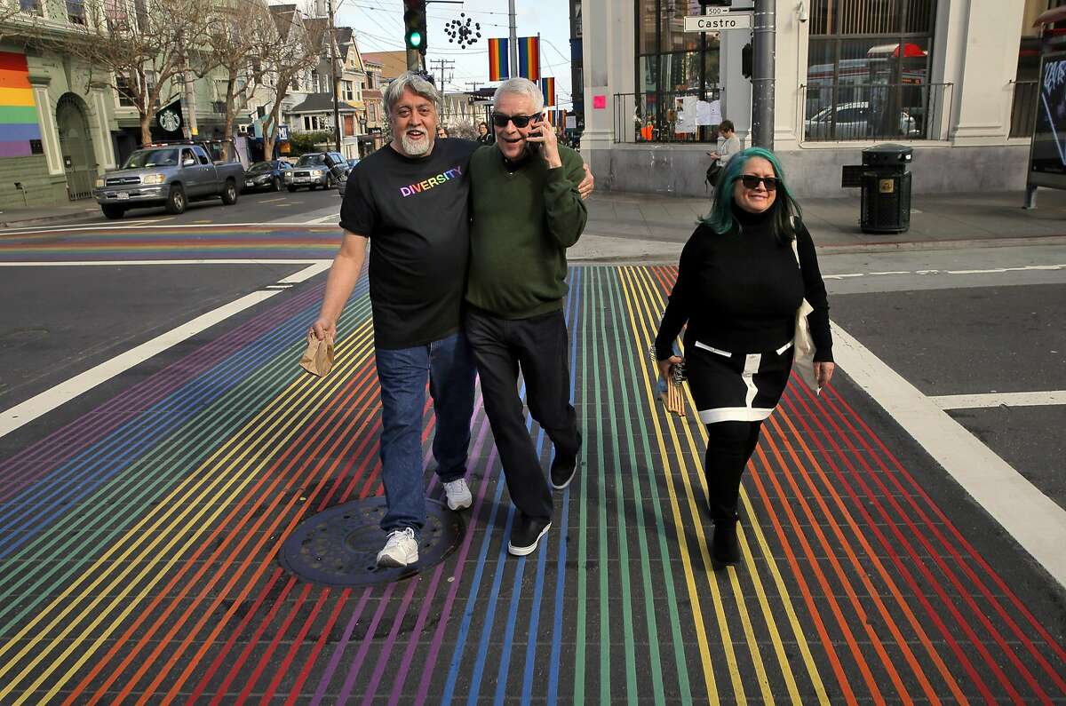Cleve Jones, center, hugs Gilbert Baker, left, who in 1978 created the Rainbow Flag, as they walk with Jillan Tripp, right, who helped with the creation of the flag in the Castro District in San Francisco, Calif., on Thursday, February 16, 2017. Jones, who first came to San Francisco in 1972, is one of four real-life queer liberation activists whose stories are being worked into a docu-drama around the movement on ABC called "When We Rise." Cleve worked under Harvey Milk and started the AIDS quilt. He's also active in labor movement work.