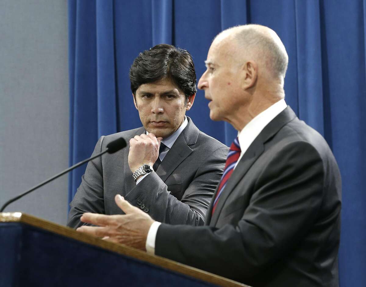 Senate President Pro Tem Kevin de Leon, D-Los Angeles listens as Calif. Gov. Jerry Brown, discusses the scaling back of a proposal to address climate change that he supported during a news conference, Wednesday, Sept. 9, 2015, in Sacramento, Calif. Citing opposition from the oil industry, de Leon, said he was dropping a mandate in his bill, SB350, that the state cut petroleum use by 50 percent.(AP Photo/Rich Pedroncelli)