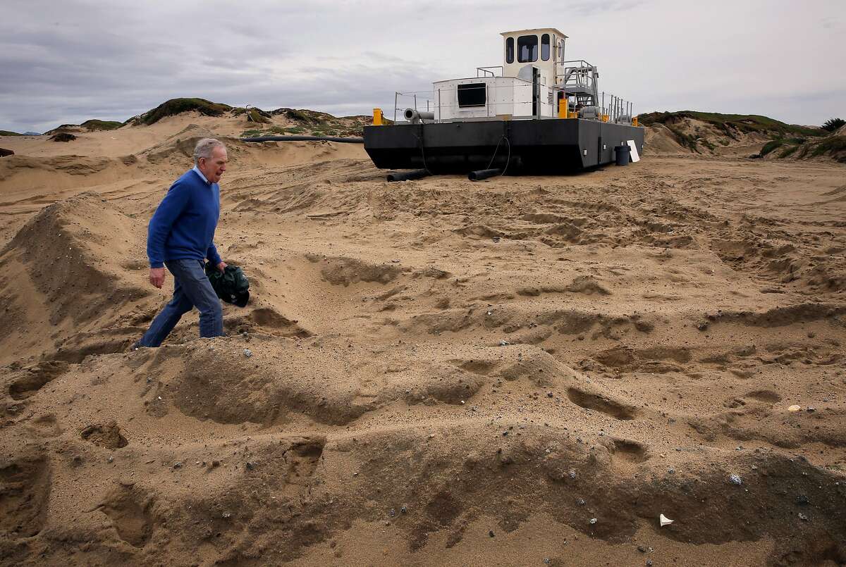 Edward Thornton, a coastal engineer with the Naval Post Graduate School walks past a dredge owned by Cemex, which removes more than 200,000 acre feet of beach sand a year along the Monterey Bay coastline in Marina, Ca., as seen on Wednesday Feb. 8, 2017,