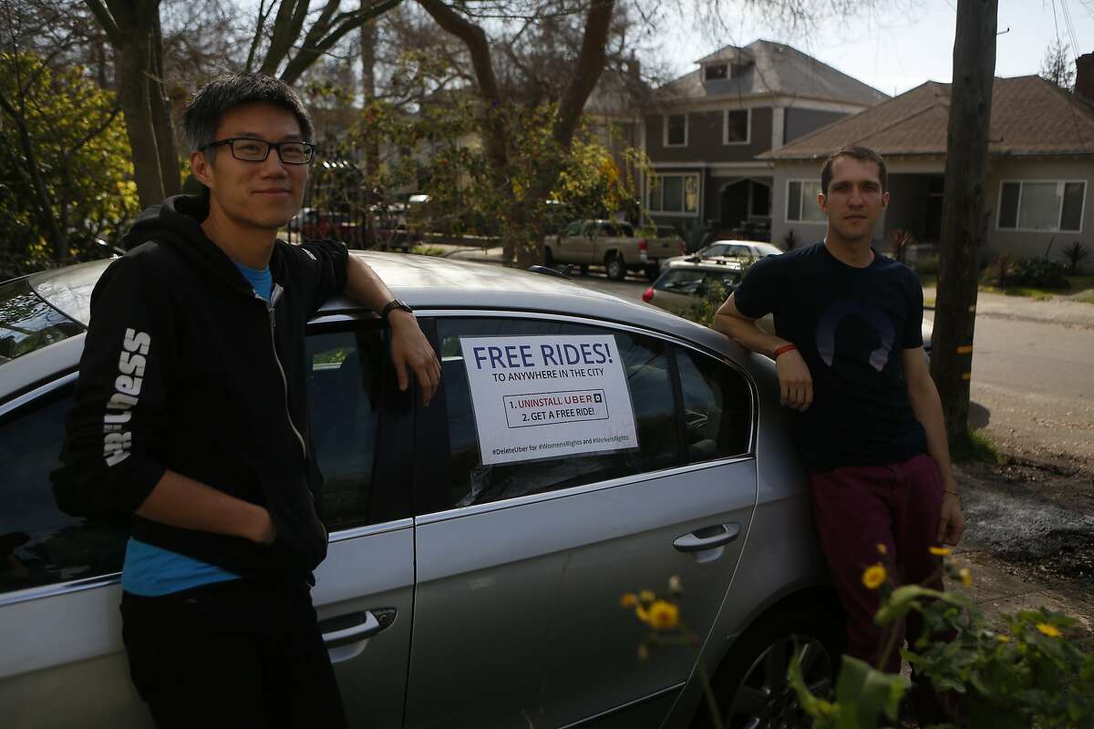 Ka-Ping Yee, left, and Michael Morgenstern, right, stand in front of their car with a sign reading, Free Rides!" before driving around offering people free rides as an alternative to using Uber, on Friday, Feb. 24, 2017, in Berkeley, Calif.