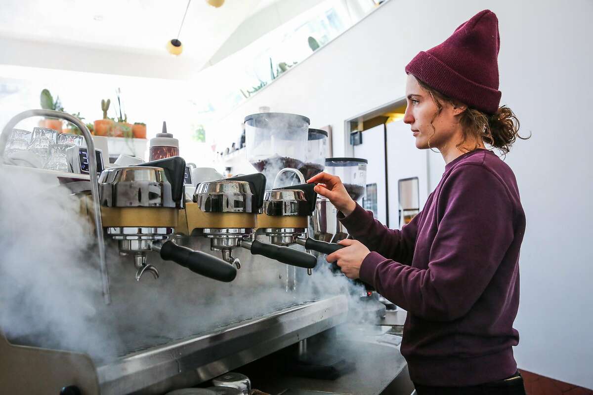 Barista Megan Kepnach demonstrates how they clean the coffee heads with water at Ritual coffee in the Haight neighborhood in San Francisco, California, on Thursday, Feb. 23, 2017.